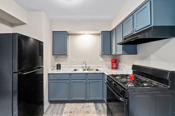 A kitchen with blue cabinets and a black stove and refrigerator